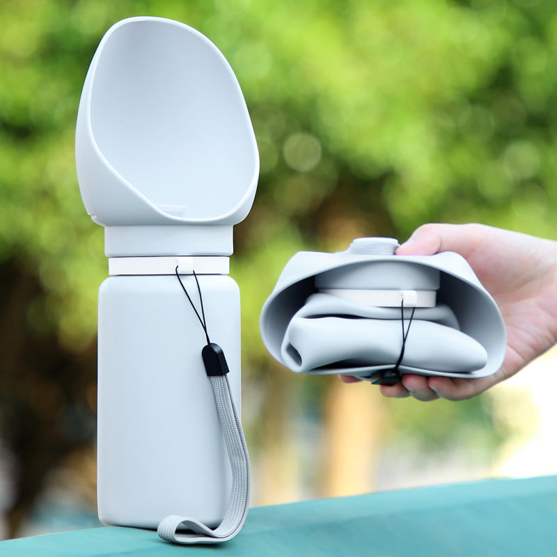 Gourde pliable grise en silicone repliée dans la main, avec cordon de transport